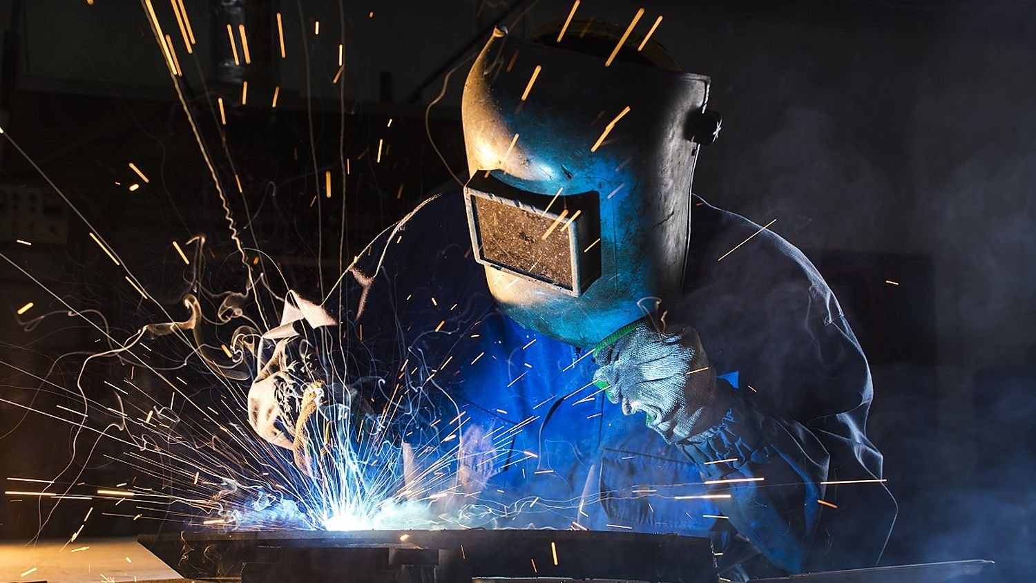 Welder joining a steel assembly with sparks flying at the AV FAB.TECH fabrication workshop
